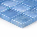 A blue glass mosaic sheet tile about to be laid by Splashback Kings tilers